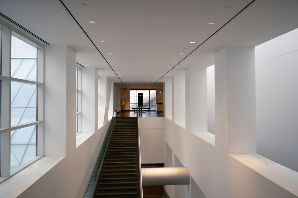 A clean interior staircase in a modern building with plain handrails and clear treads.
