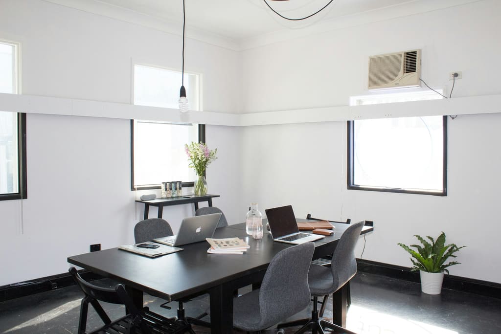 An open-plan workspace with tidy desks, soft daylight and clear circulation space.