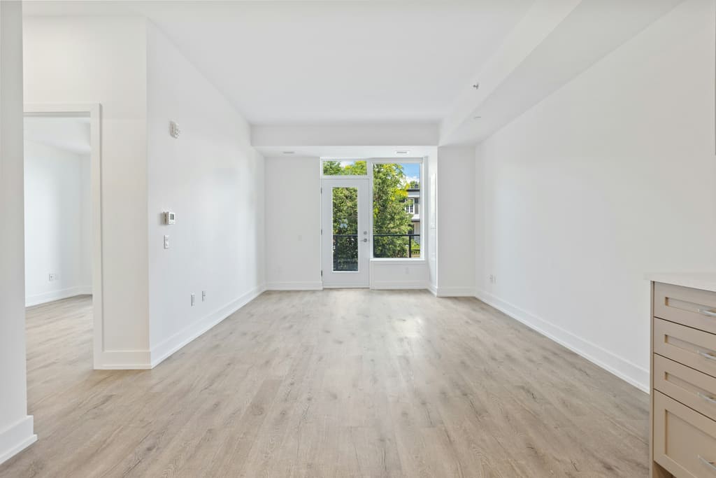 An empty rental property interior with bare floors, plain walls and daylight from a window.