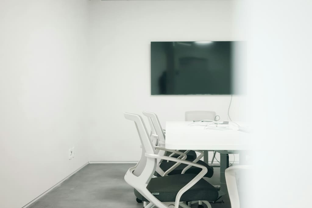 A plain meeting room with a clear table and simple chairs, ready for use.