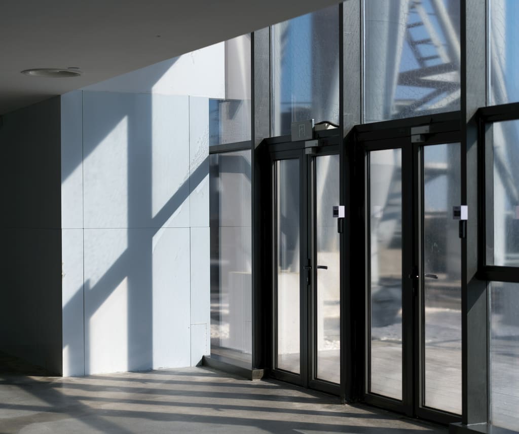 A building entrance seen from inside, with glass doors and a clear, open floor.
